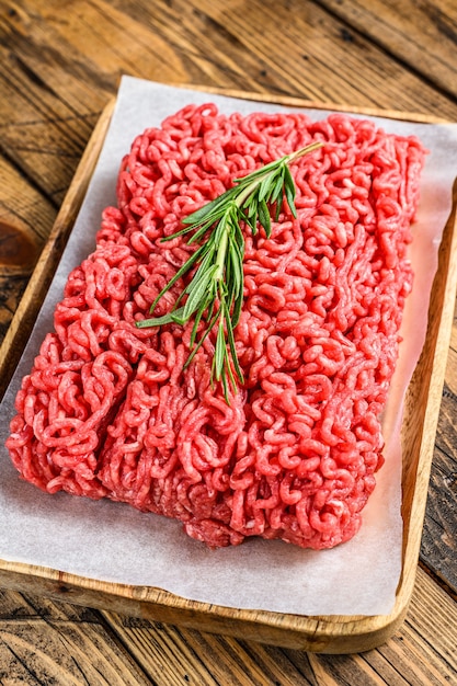 Fresh Raw mince beef, ground meat on butcher paper. wooden background. Top view.