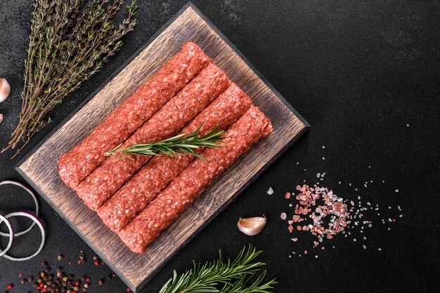 Fresh raw mince for grilled kebab with spices and herbs on a dark concrete background