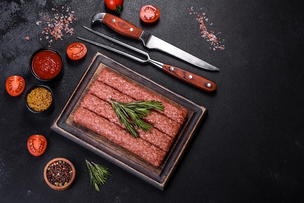 Fresh raw mince for grilled kebab with spices and herbs on a dark concrete background