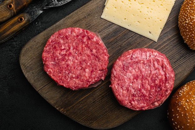 Fresh raw minced homemade farmers grill beef burgers on black dark stone table background top view flat lay