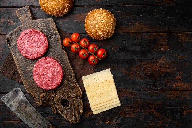 Freschi crudi macinati fatti in casa bistecca di manzo alla griglia hamburger sul vecchio tavolo in legno scuro sfondo vista dall'alto piatto laici con copia spazio per il testo