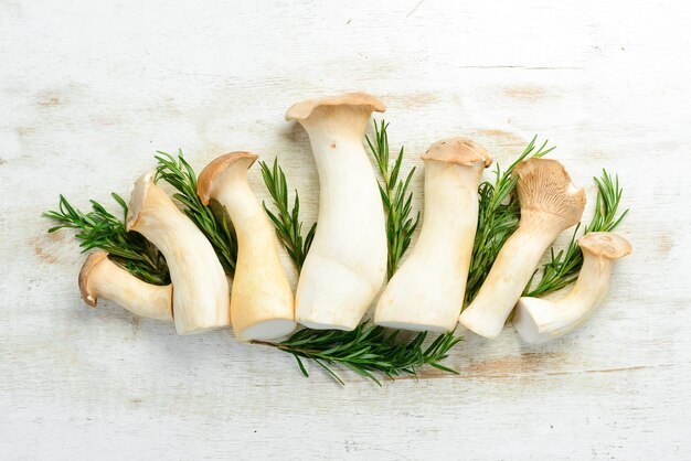 Foto funghi crudi freschi king oyster o eringi su sfondo di legno bianco funghi vista dall'alto