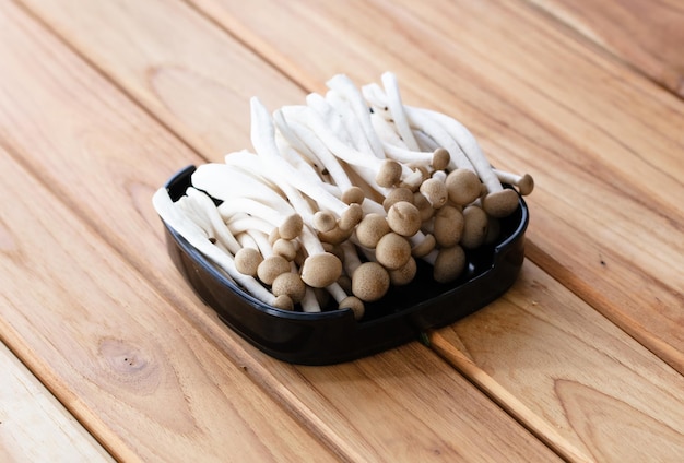 Fresh raw mushrooms sliced on square plate isolated on wooden background shabu hot pot ingredients