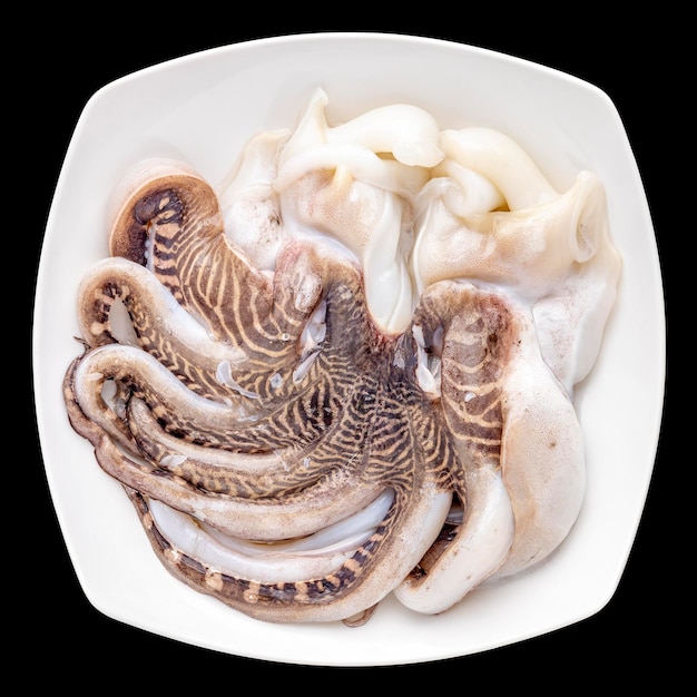 Photo fresh raw octopus in plate isolated on black background ingredient for seafood cooking top view flat lay square ratio