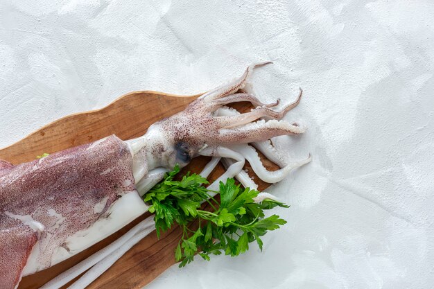 Fresh raw octopus with parsley on cutting board