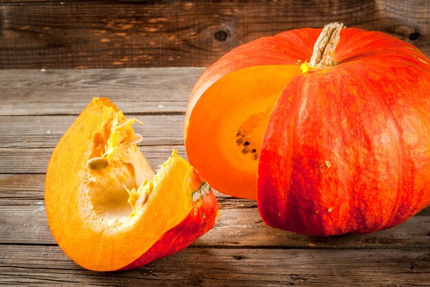 Fresh raw orange organic pumpkin on an old rustic wooden table