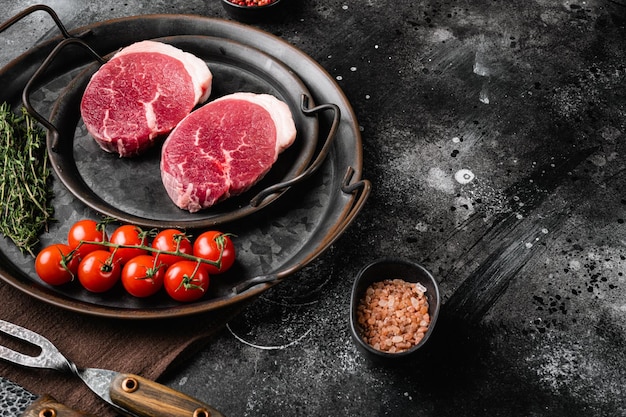 Fresh raw organic beef steak set on black dark stone table background with copy space for text