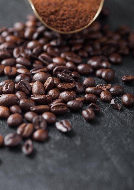 Fresh raw organic coffee powder and beans in vintage steel scoop on black background Macro