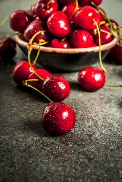 Fresh raw organic seasonal fruits. Cherry with drops of water on a dark stone table.  copyspace