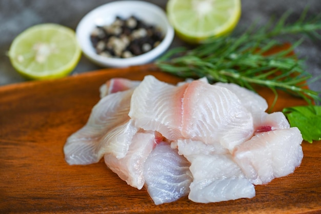 Fresh raw pangasius fish fillet with meat dolly fish tilapia striped catfish fish fillet on wooden board with ingredients celery for cooking