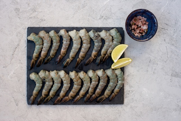 Gamberi sgusciati crudi freschi con spezie e limone su una tavola di pietra. i frutti di mare sani sono una fonte di proteine. disteso.