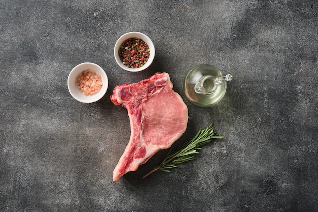 Fresh Raw pork loin with bone with salt and pepper over grey background