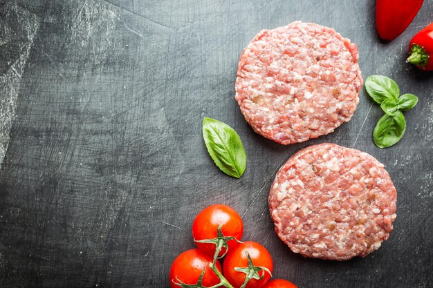 Foto tortini di hamburger di manzo prime black angus crudo fresco su sfondo nero. vista dall'alto.