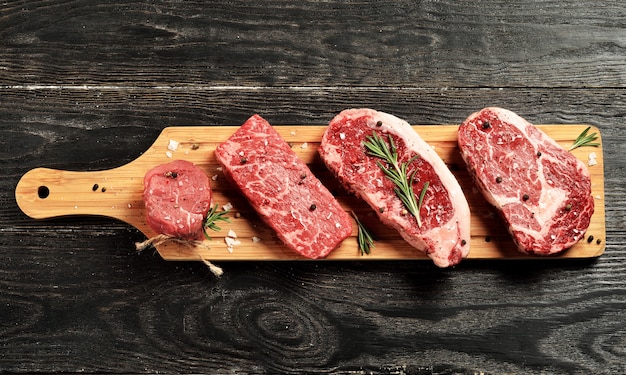 Fresh raw prime black angus beef steaks on wooden board: tenderloin, denver cut, striploin, rib eye