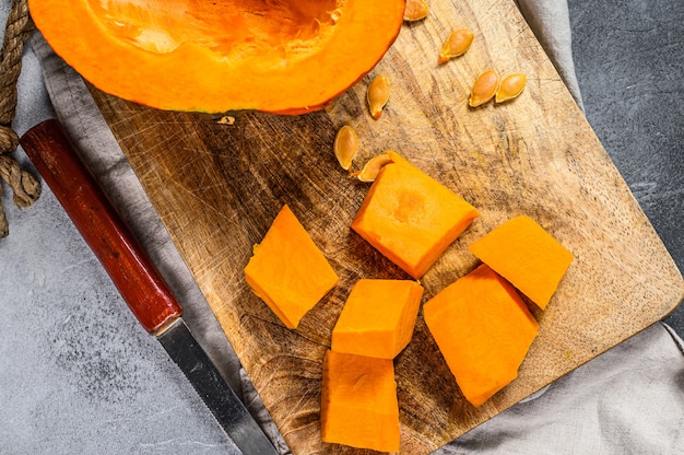 Foto zucca cruda fresca su un tagliere, tagliata a cubetti.