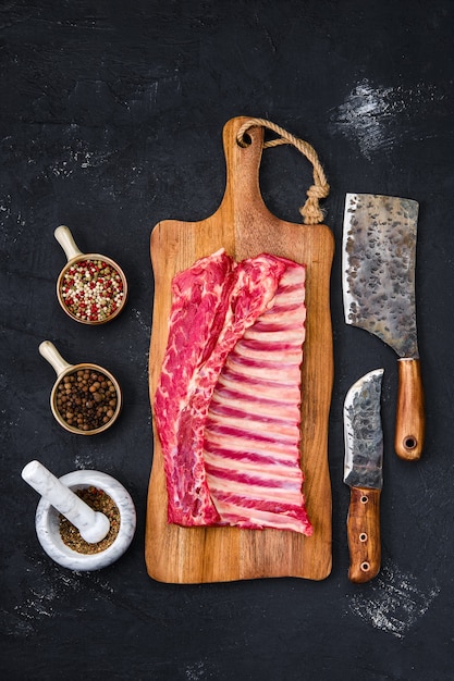 Fresh raw rack of lamb on wooden cutting board with herbs and seasoning