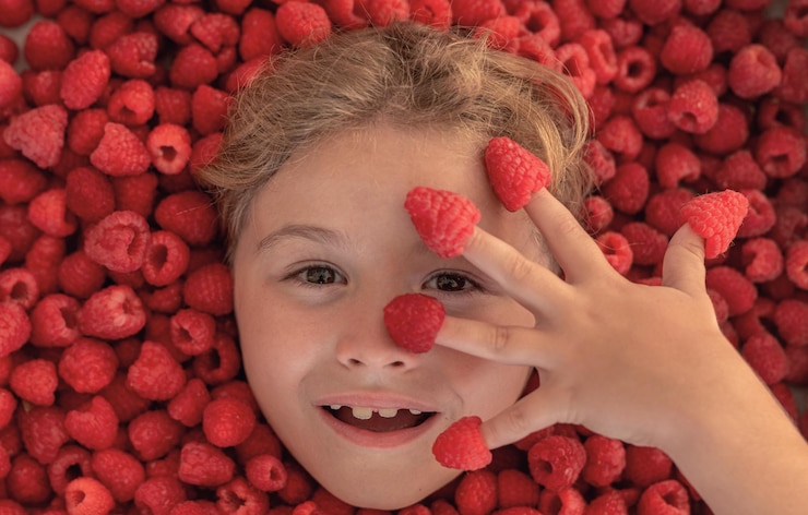 Photo fresh raw raspberry near kids face raspberri macro top view of collection raspberries raspberries background