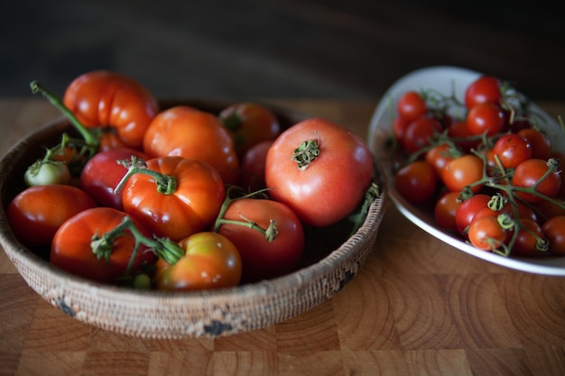 Photo fresh raw red tomatoes in basket on wooden table