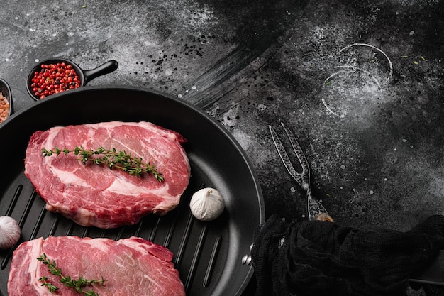 Fresh raw Rib eye Steak with seasonings set, on black dark stone table background, with copy space for text