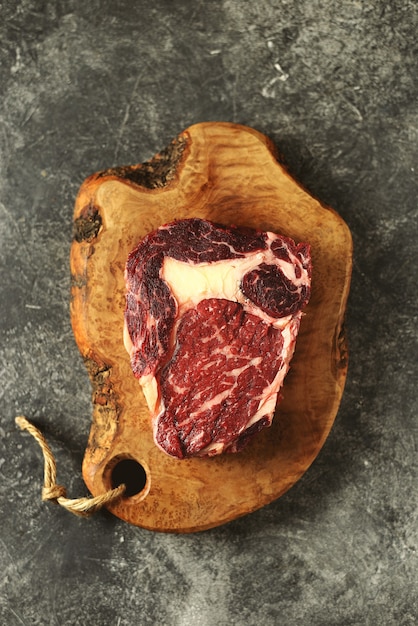 Fresh raw rib eye steak on a wooden board