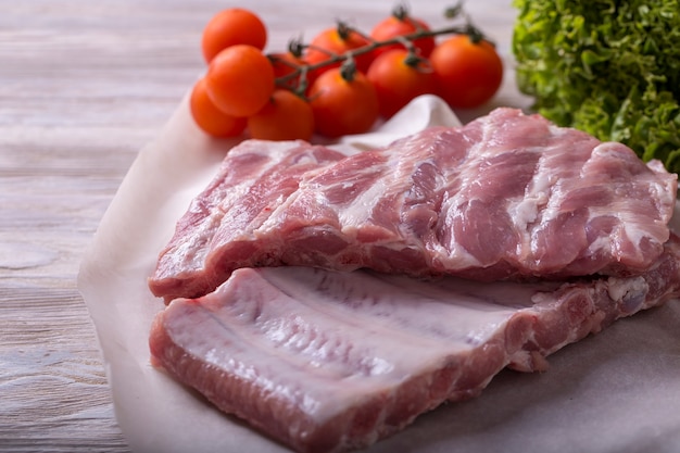 Fresh raw ribs with vegetables on crumpled paper.