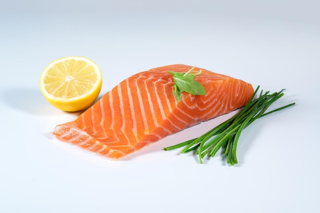 Fresh raw salmon fish fillet, herbs and lemon on isolated background