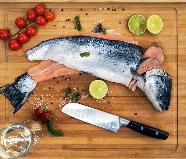 Fresh raw salmon fish on the kitchen wooden board with spices and lime