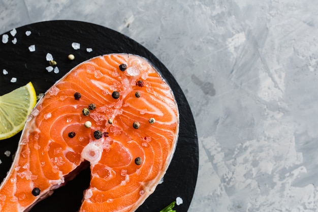 Fresh raw salmon fish steak with spices on stone background