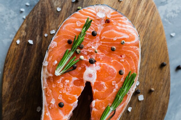 Trancio di pesce di color salmone crudo fresco con le spezie sul bordo di legno