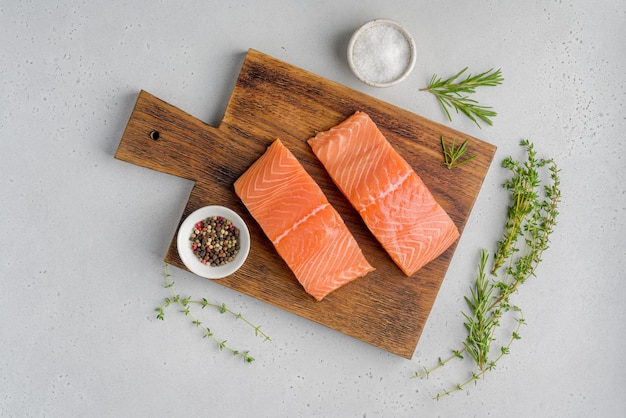 Fresh raw salmon humpback fillet on old wooden board rosemary thyme salt pepper