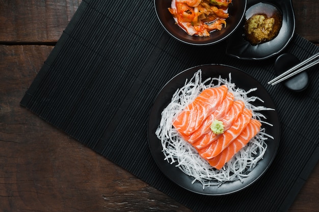 Fresh raw salmon sashimi on white shredded radish in Japanese style on wooden table.