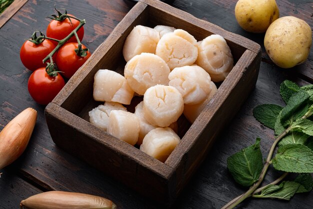 Fresh raw scallops ingredients ready for cooking, on dark wooden table