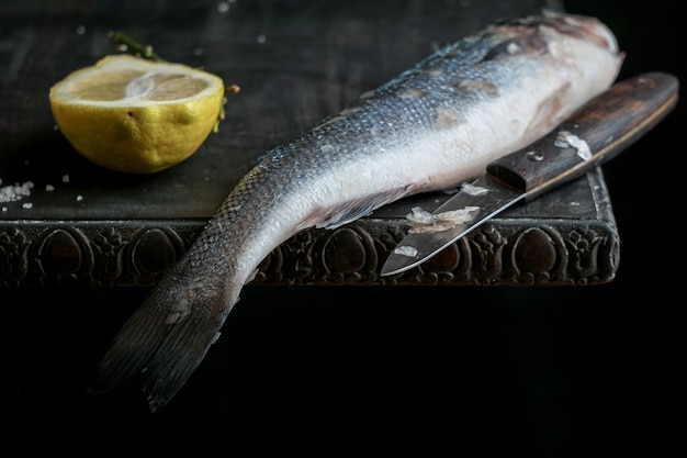 黒い木製のテーブルの上の新鮮な生のシーバスの魚