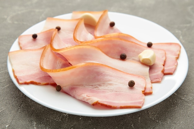 Fresh raw slices bacon on plate.