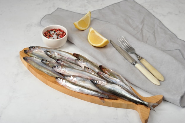 Fresh raw smelt on a wooden Board with lemon