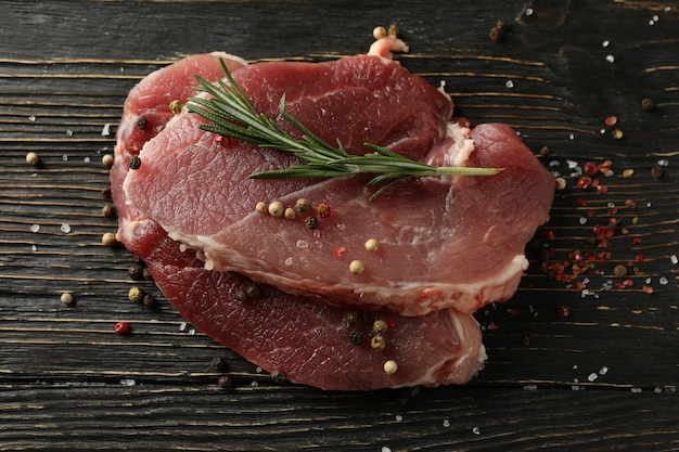 Fresh raw steak meat with herbs and spices on wooden table