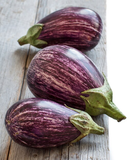 Fresh raw striped eggplants on an old wooden table