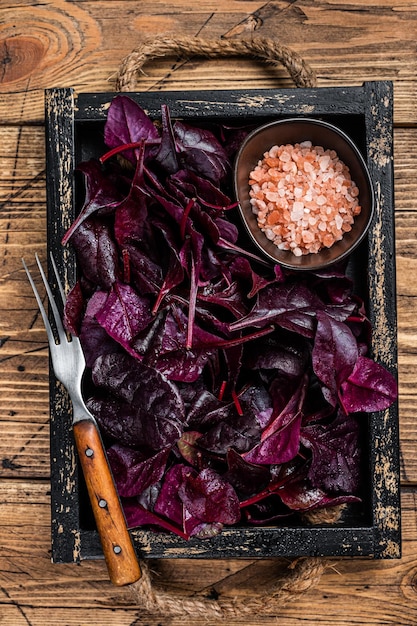 Photo fresh raw swiss ruby or red chard salad leafs in a wooden tray. wooden background. top view.