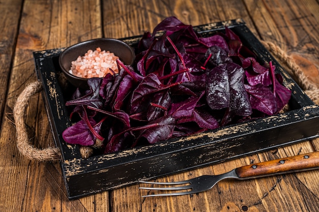 Photo fresh raw swiss ruby or red chard salad leafs in a wooden tray