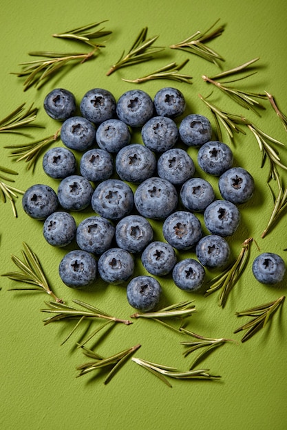 Fresh raw tasty blueberries with leaves isolated on green background copy space