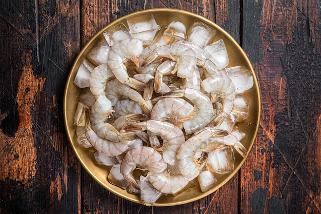 Fresh Raw tiger white shrimp prawn peeled with tail on ice Wooden background Top view