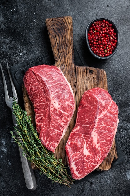 Fresh Raw Top Blade or flat iron beef meat steaks on a butcher cutting board