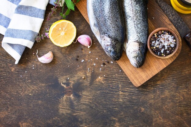 木製のテーブルで新鮮な生のマスの魚とピクルスの材料焼き魚の調理