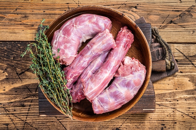 Fresh Raw Turkey necks meat in a wooden plate with thyme. wooden background. Top View.