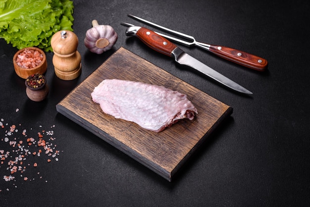 Fresh raw turkey wing with spices and herbs on a wooden cutting board