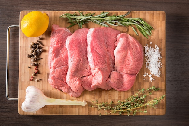 Fresh and raw veal meat Steaks with seasonings in a row ready to cook