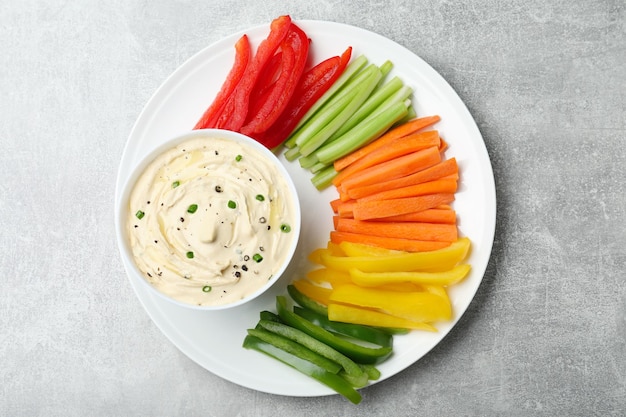 Fresh raw vegetable sticks and sauce on grey table top view