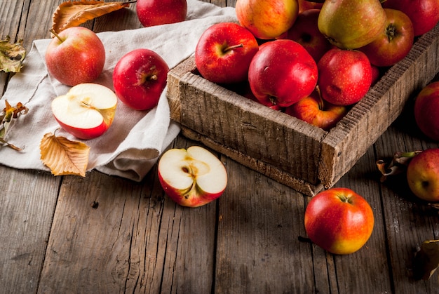 Fresh raw whole and sliced organic farm red apples in old wooden bow, old wooden rustic table,  copyspace top view