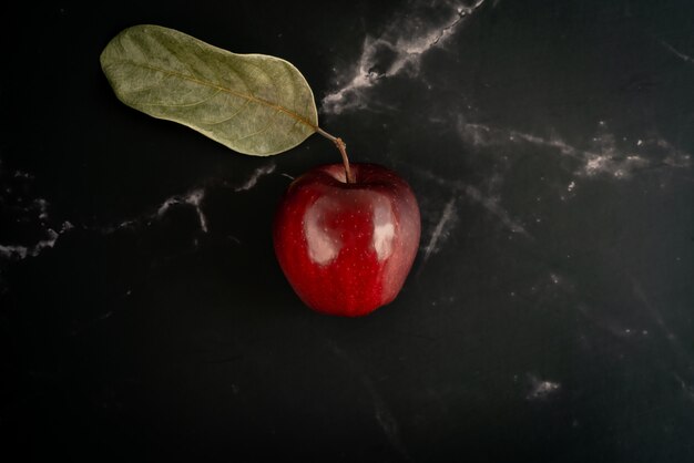 Photo fresh red apple with green leaf  lie on a black marble background. top view flat lay composition.