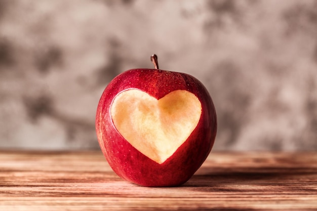 Fresh red apple with heartshaped cut out on wooden table